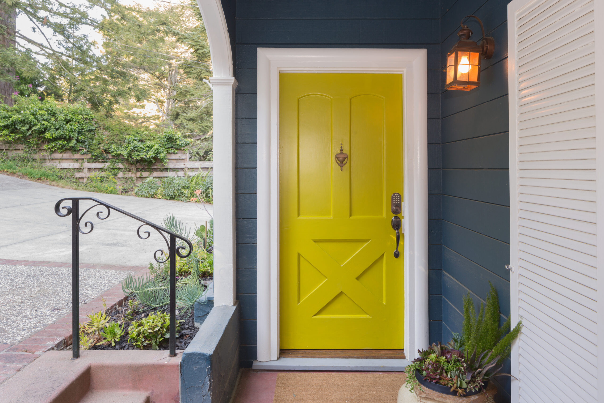 Yellow entry door with keypad on dark blue siding