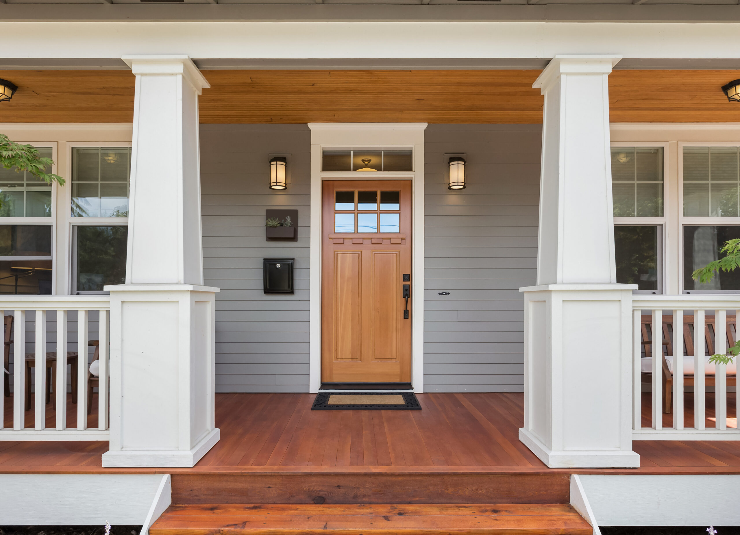 Wood entry door with wood porch and white pillars