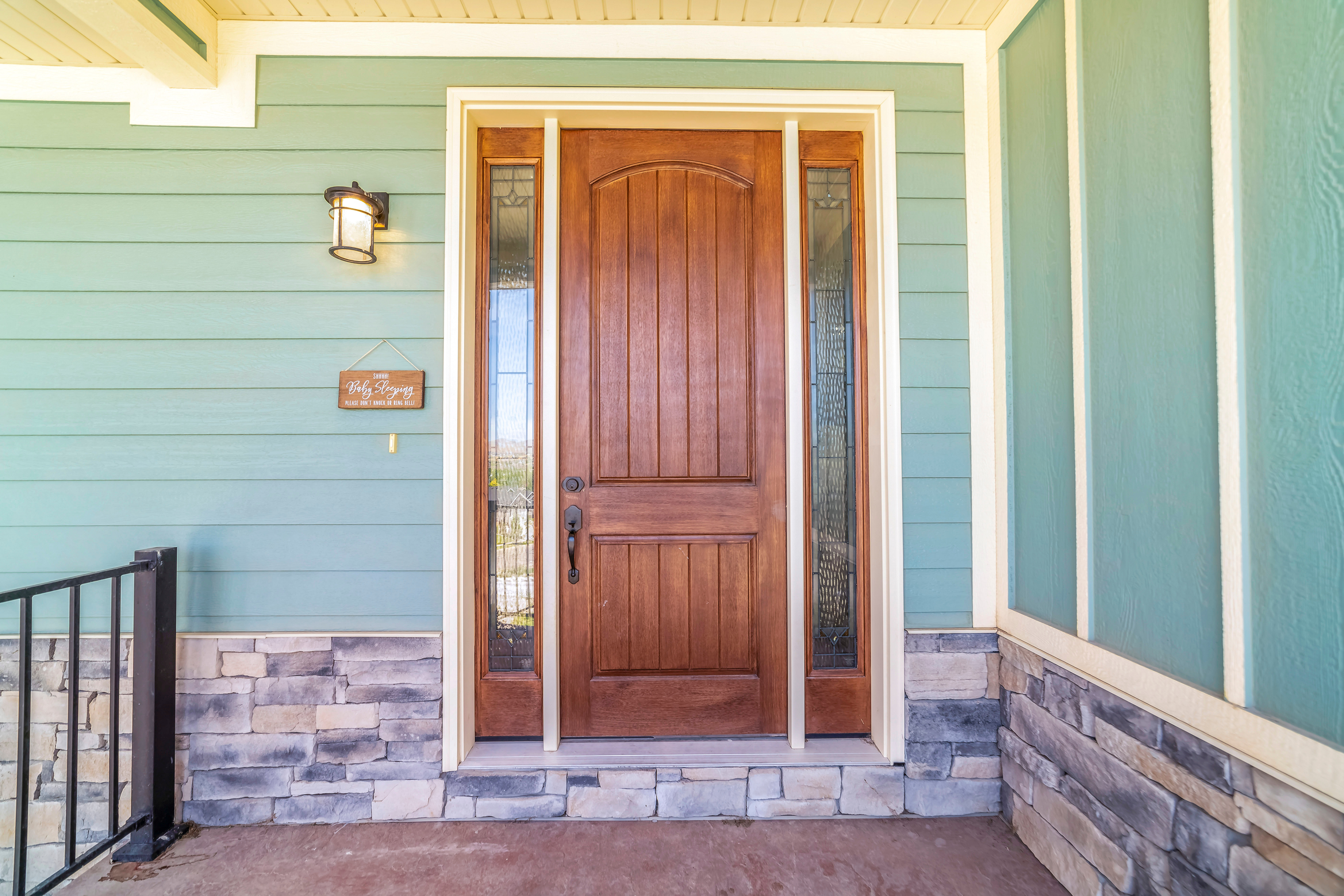 Wood door with glass on sides aquamarine siding and outdoor light