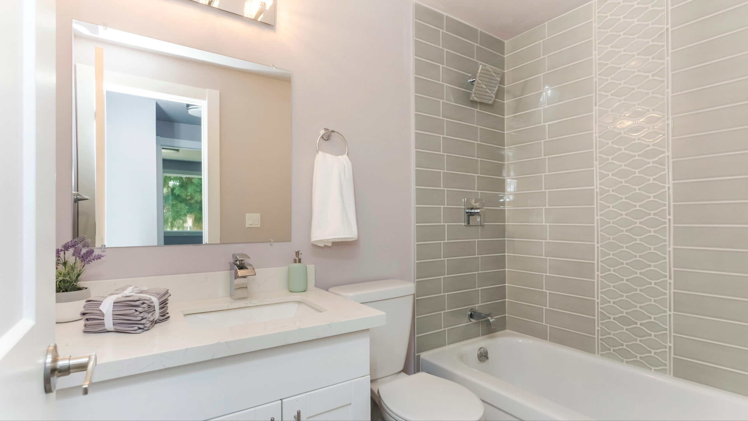 A bathroom with a white bathtub and gray tile