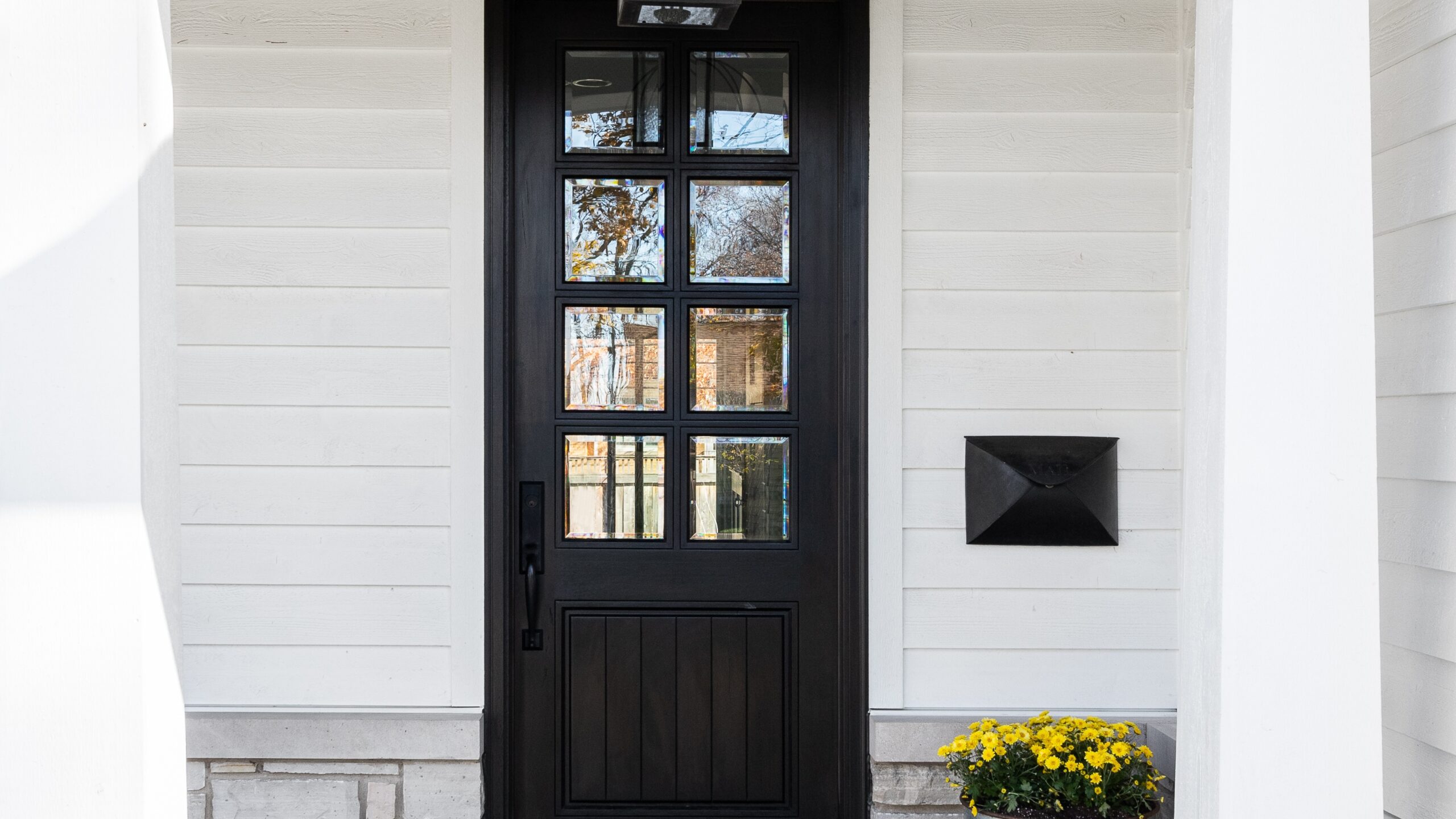 A black door in a home with white siding