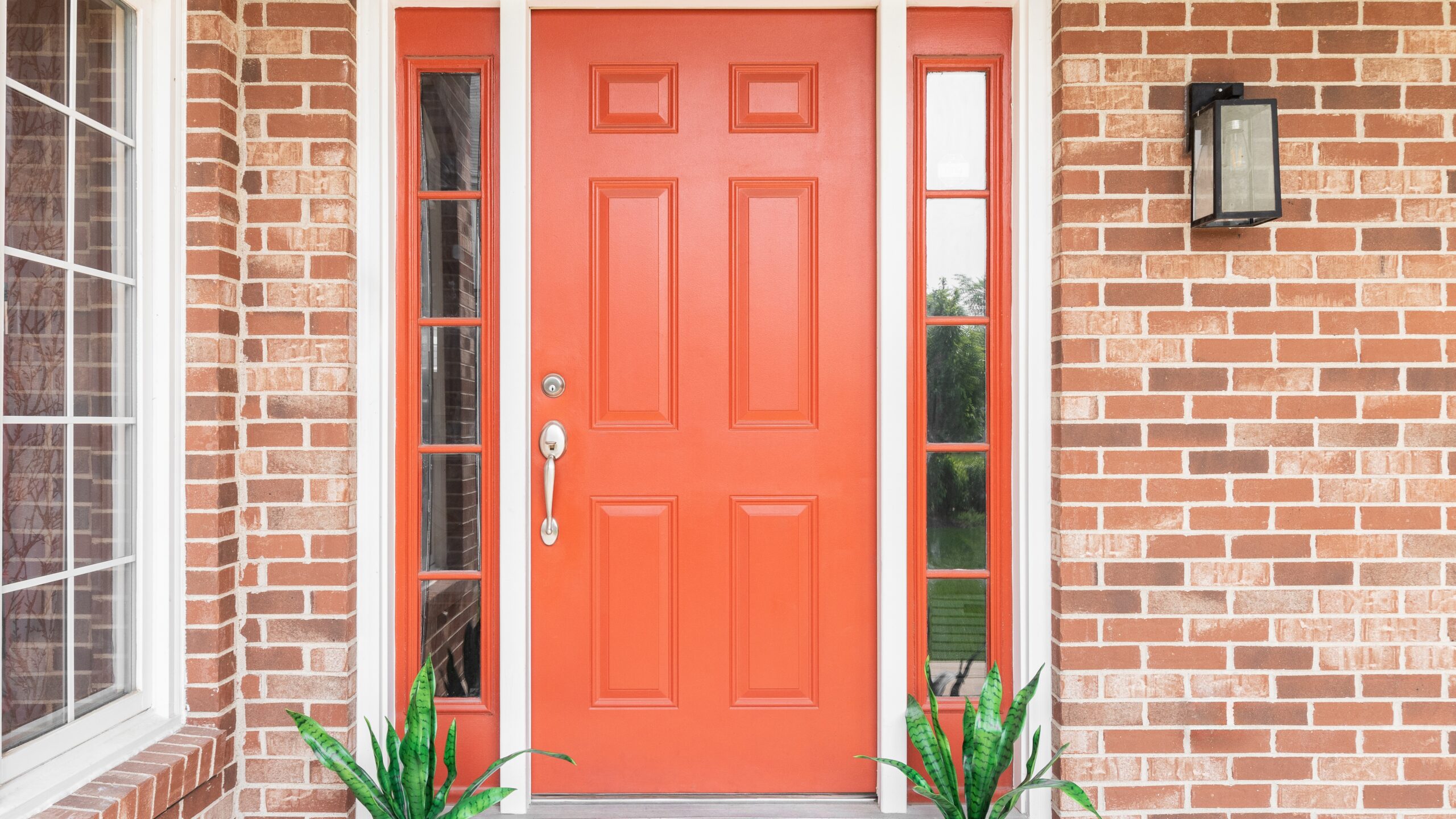 A red door in a home with brick siding
