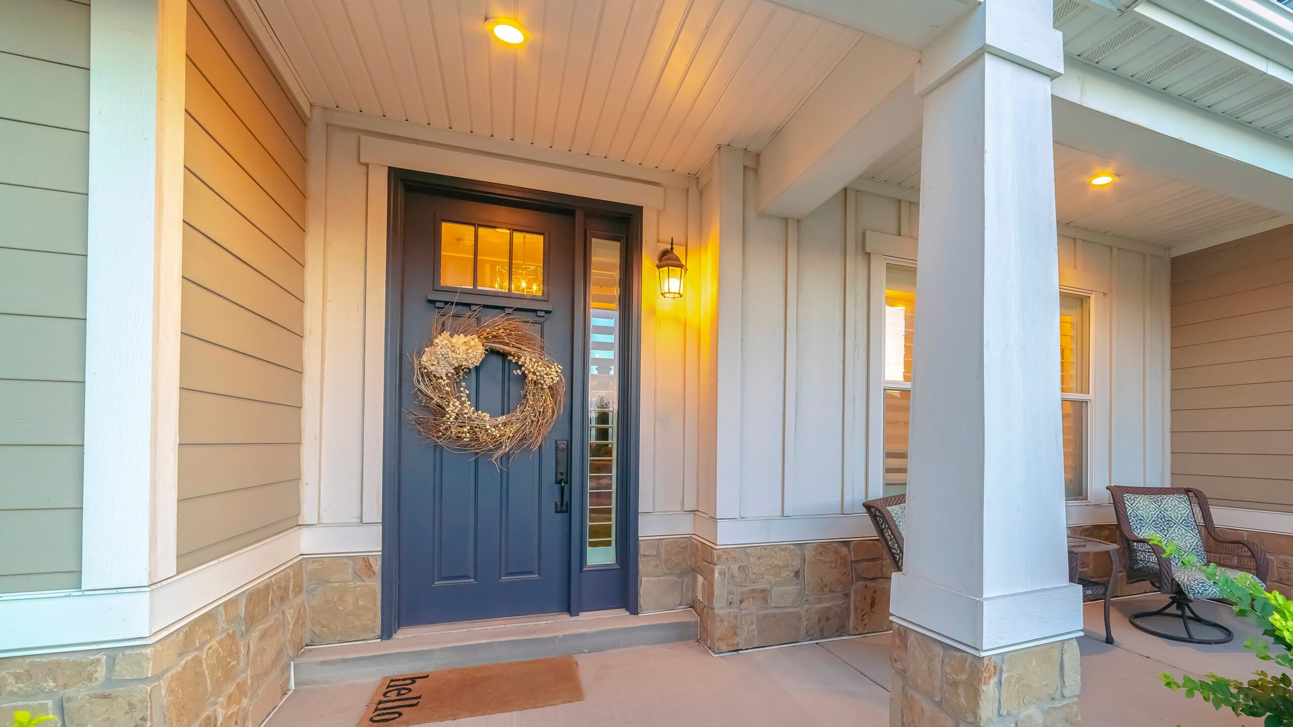 A blue door with glass features and a brown wreath in a home with detailed white siding