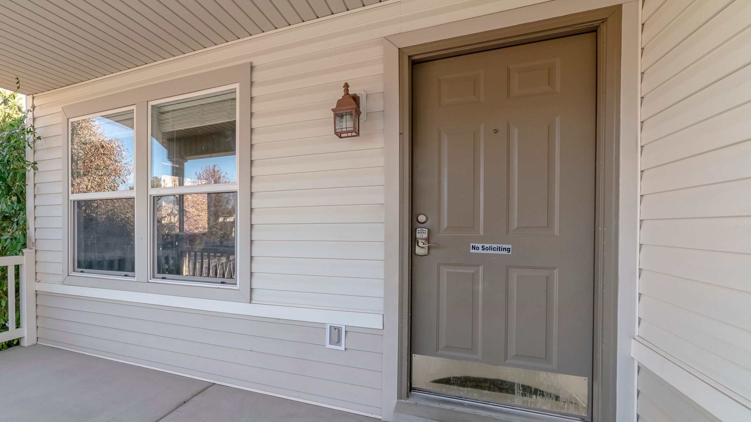 A brown entry door in a home with white siding