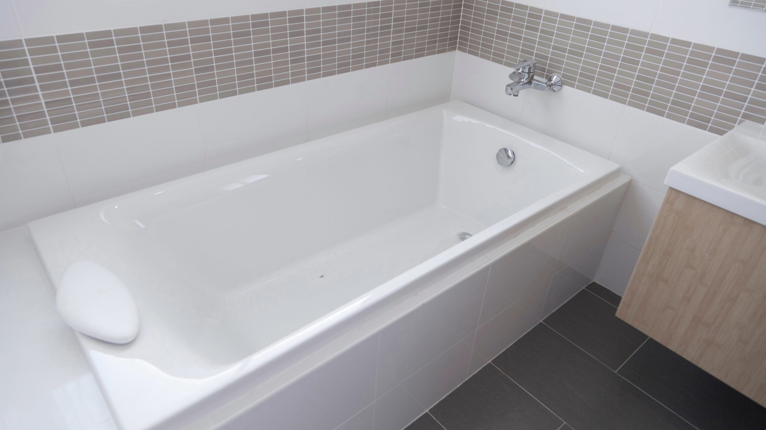 A white bathtub with a tile surround