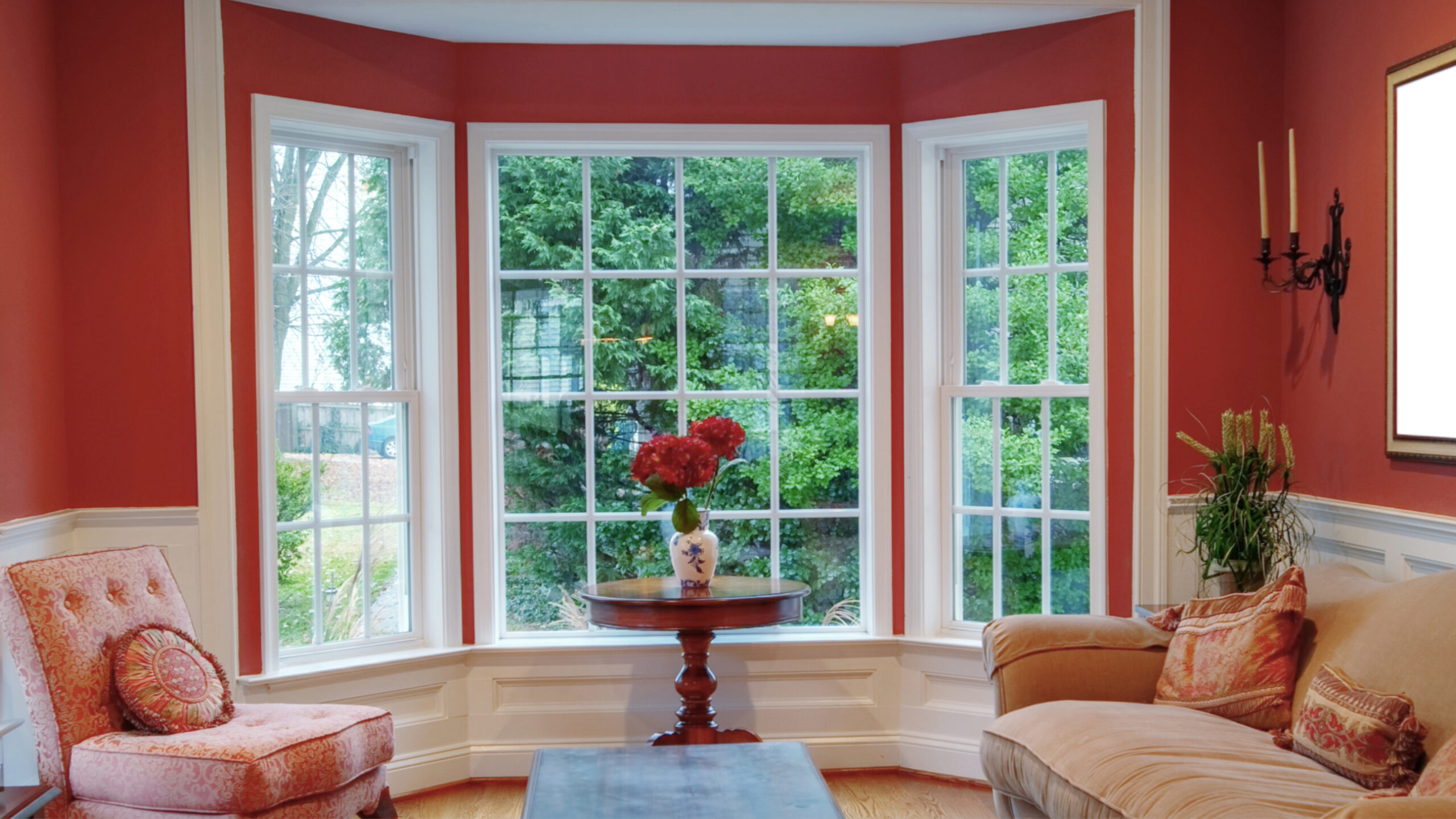A window with white trim in a room with red walls