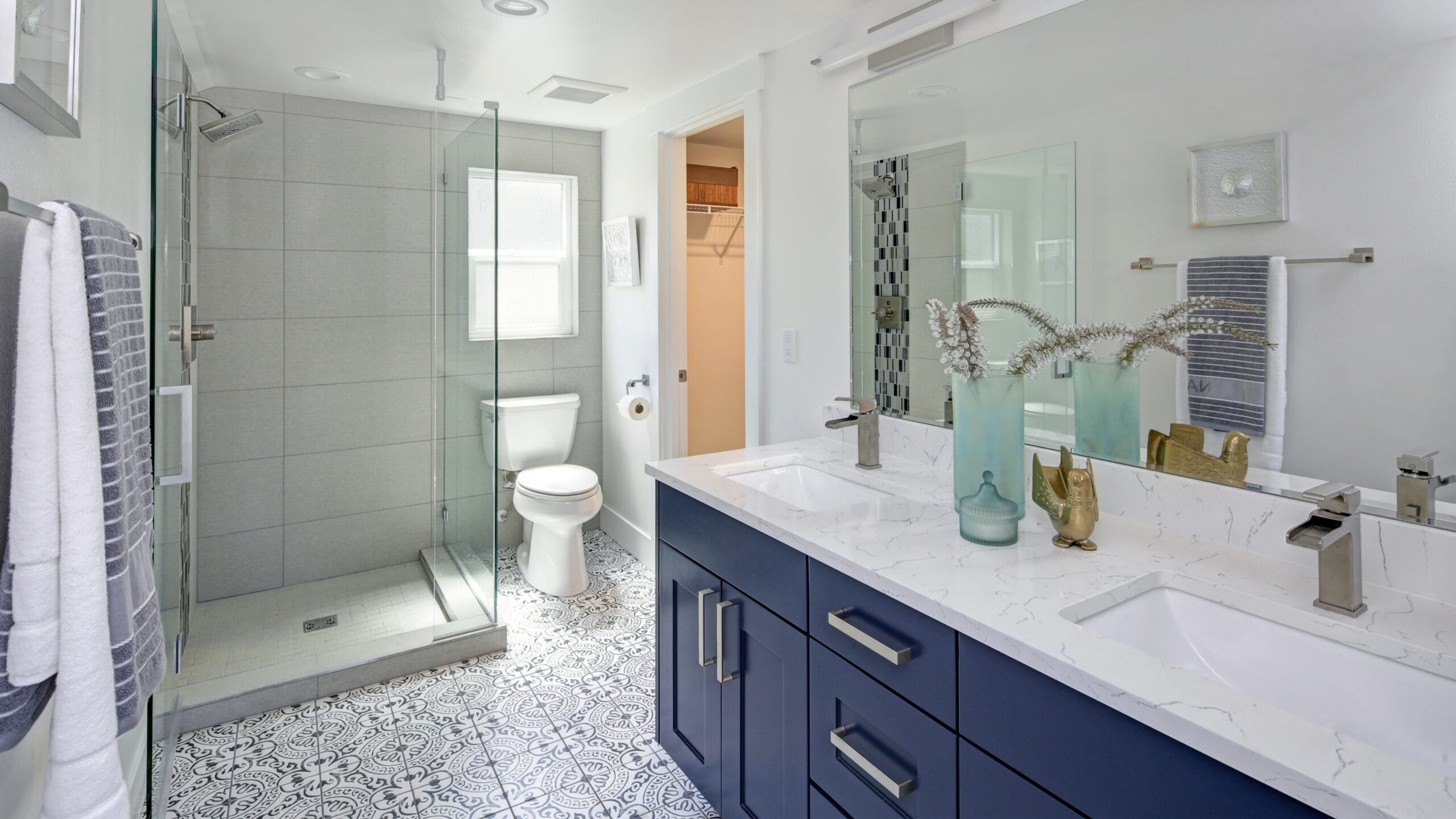 A bathroom with tile floors, a blue vanity, and walk-in shower