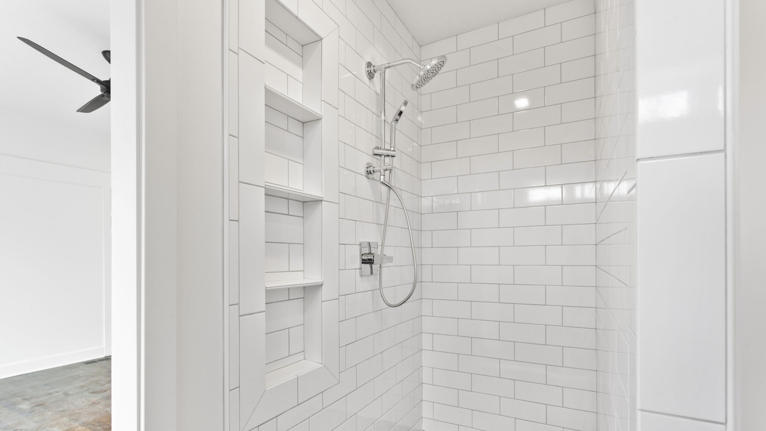 A shower with white subway tile and built-in shelving