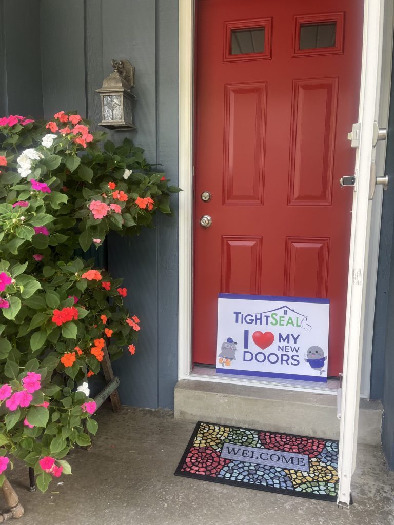 Red six-panel entry door with a white storm door, installed on a Greendale, WI home by TightSeal Exteriors & Baths