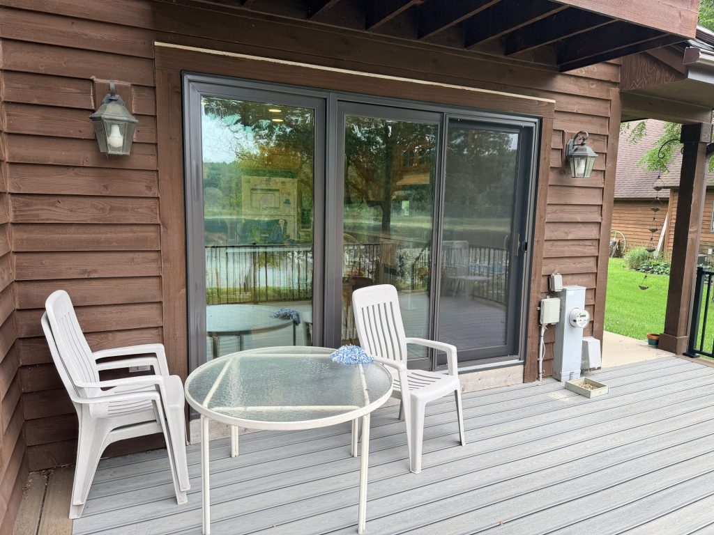 Three-panel sliding patio door with dark bronze frames, installed on an Oconomowoc, WI home with a deck by TightSeal Exteriors & Baths